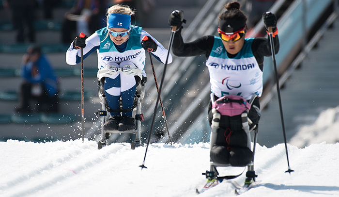 Kaksi kelkkahiihtäjää vierekkäin paralympialaisissa kamppailemassa voitosta.