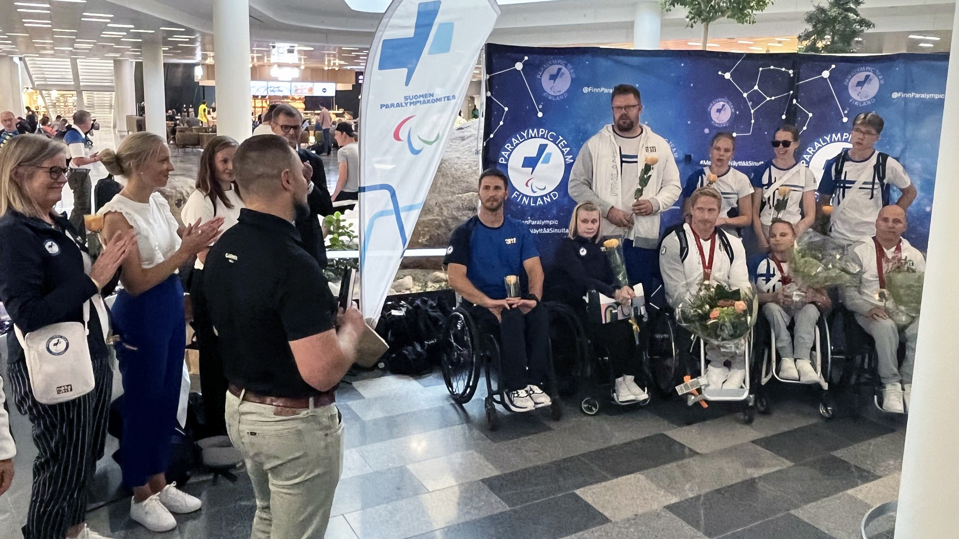 Paralympiajoukkueen urheilijoita lentokentällä vastaanottoseremoniassa.